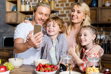 happy family with two kids taking selfie while having breakfast at home の写真素材