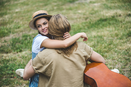 beautiful young couple with guitar embracing in parkの写真素材