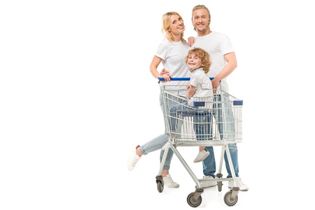 cheerful parents and son in shopping cart looking at camera isolated on whiteの写真素材