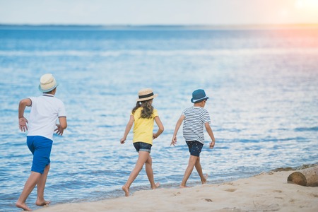 back view of kids in casual clothing walking on beach togetherの写真素材