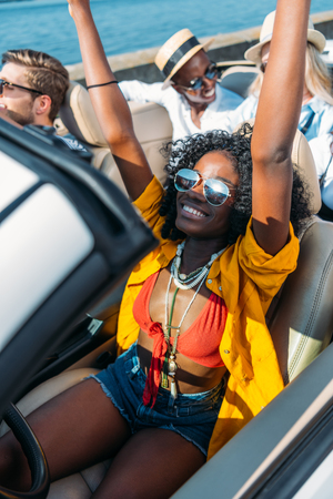 multicultural young happy friends riding car together at seasideの写真素材