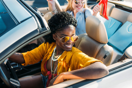 selective focus of young stylish african american woman riding car with friendの写真素材