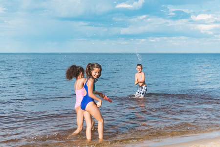 little children with water toys playing together at seasideの写真素材