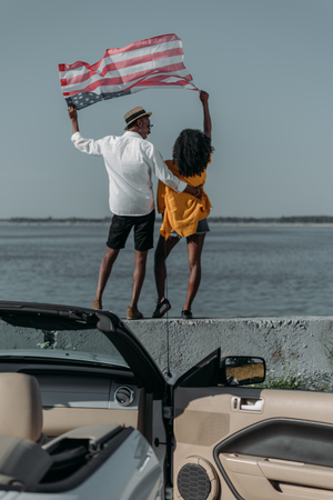 back view of african american couple with american flag standing on parapet togetherの写真素材