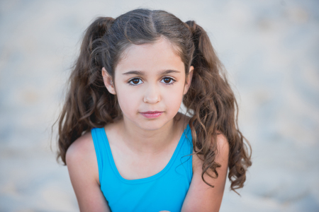portrait of little girl in swimsuit looking at camera on beachの写真素材