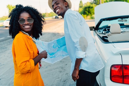 smiling african american couple choosing destination on map while traveling togetherの写真素材