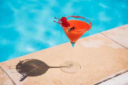 Colorful tropical cocktail with berries on edge of swimming pool の写真素材
