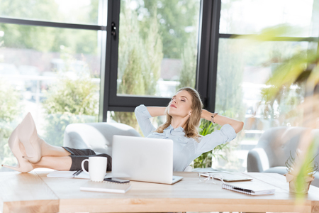 young businesswoman resting during work at workplace with laptop in officeの写真素材