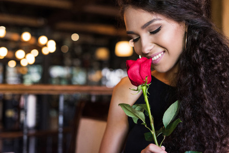 Young beautiful woman with red rose sitting in restaurantの写真素材