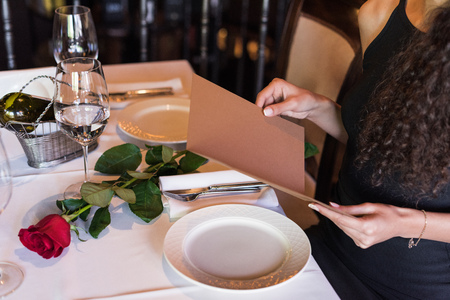 Cropped view of woman with menu sitting at table in restaurantの写真素材