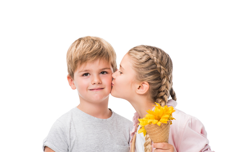 adorable little girl holding waffle cone with flowers and kissing cute boy isolated on whiteの写真素材