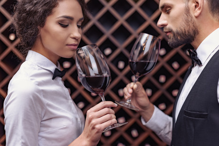 Two sommeliers, male and female tasting red wine in cellarの写真素材