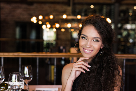 Portrait of young beautiful woman sitting in restaurant, smiling and looking at camera の写真素材
