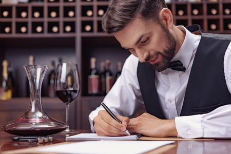 Young handsome man sommelier tasting red wine in cellarの写真素材
