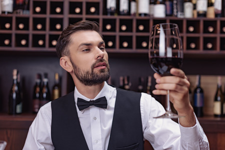 Young handsome man sommelier tasting red wine in cellar
