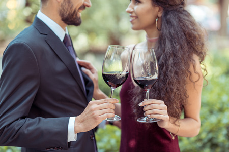 Happy young coupe standing with red wine in garden の写真素材