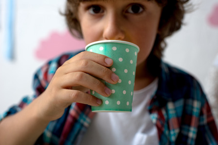 close-up view of cute little boy drinking from paper cupの写真素材