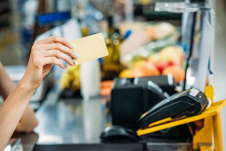 partial view of shop assistant holding credit card in hand at cash point in supermarketの写真素材