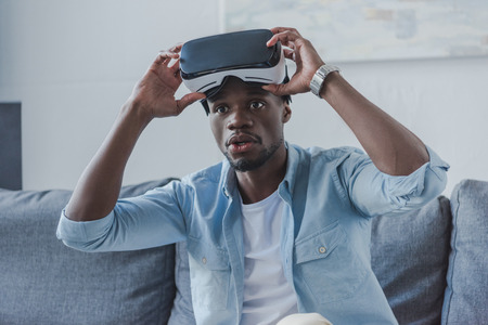 African american man using virtual reality headset at homeの写真素材