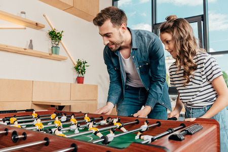 happy young father and daughter playing table footballの写真素材