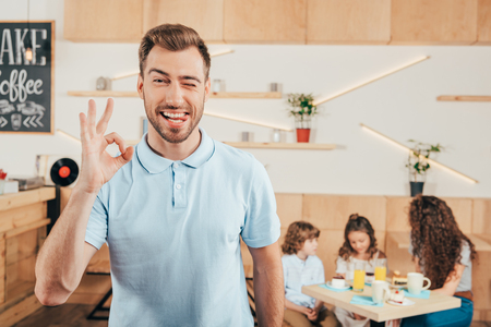 young man showing okay sign with his family blurred on backgroundの写真素材