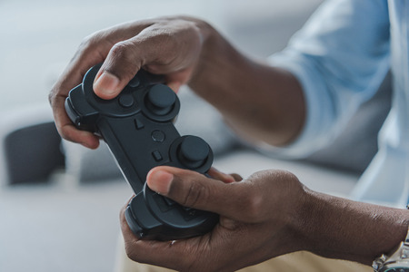Cropped image african american man playing video game with joystick at homeの写真素材