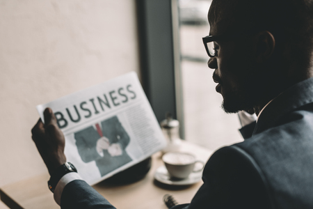 handsome african american businessman reading newspaper in coffee shopの写真素材
