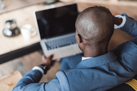back view of african american businessman working with laptop in cafe の写真素材