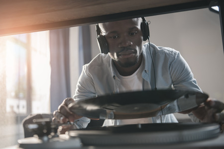 African american man playing vinyl record at home