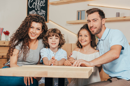 beautiful young family with two kids waiting for order in restaurantの写真素材