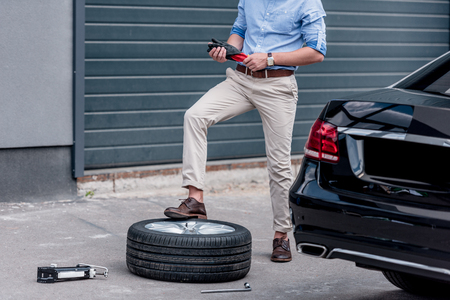 cropped view of young man changing car tire の写真素材