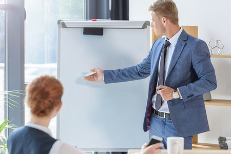 Young businessman presenting his idea by flip chart to colleagues in modern officeの写真素材
