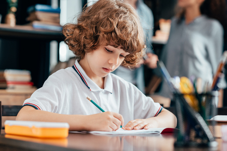 adorable curly boy doing homeworkの写真素材
