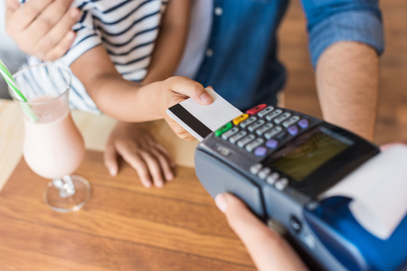 cropped shot of father and son paying with credit card in cafe