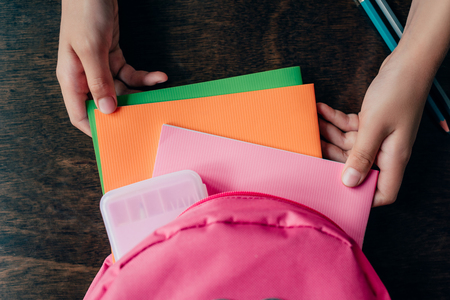cropped shot of girl pulling school supplies from backpackの写真素材