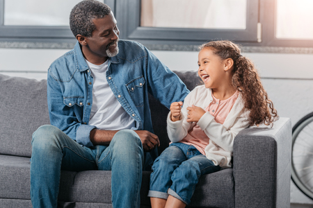 Adorable african american girl spending good time with father at homeの写真素材