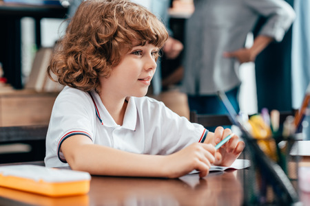 cute little boy sitting at school deskの写真素材