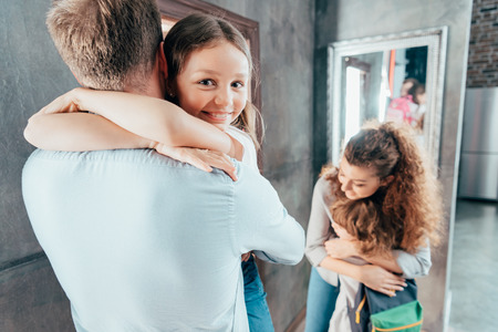 adorable parents hug kids before schoolの写真素材