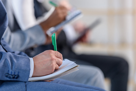 People with notepads listening to presentation in modern officeの写真素材