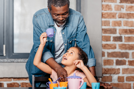 African american girl having tea party with father at homeの写真素材