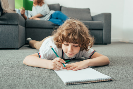 adorable little boy doing homework on floorの写真素材