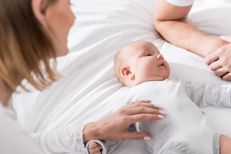 parents with cute little baby boy on bed at home  