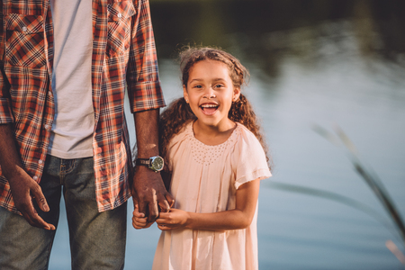 cropped view of happy african american granddaughter and her grandfather holding hands 