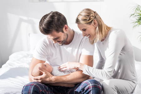 smiling parents holding little baby boy at home  の写真素材