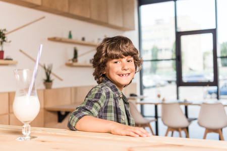 cute little boy sitting in cafe with milkshake on bar counterの写真素材