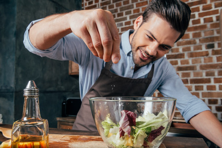 man adding salt into fresh saladの写真素材