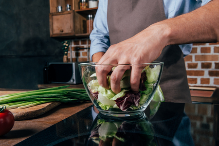 close-up shot of man mixing salad with handsの写真素材