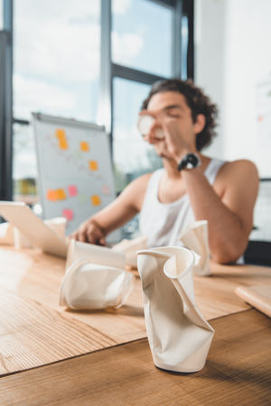 businessman in underwear drinking coffee while working on laptop at workplace in officeの写真素材
