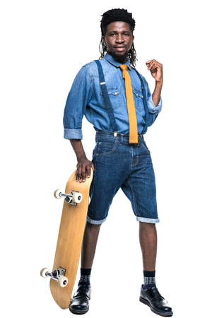 stylish african american man standing with skateboard isolated on whiteの写真素材