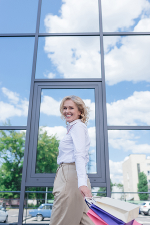 low angle view of smiling woman with shopping bagsの写真素材